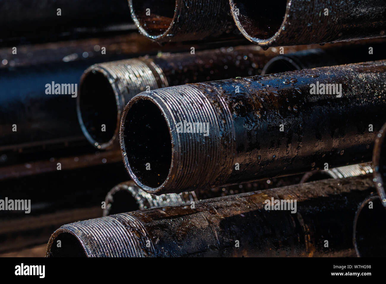 Vista di foratura involucro di tubazioni e tubi impilati in cantiere aperto del petrolio e del gas il magazzino. Foto Stock