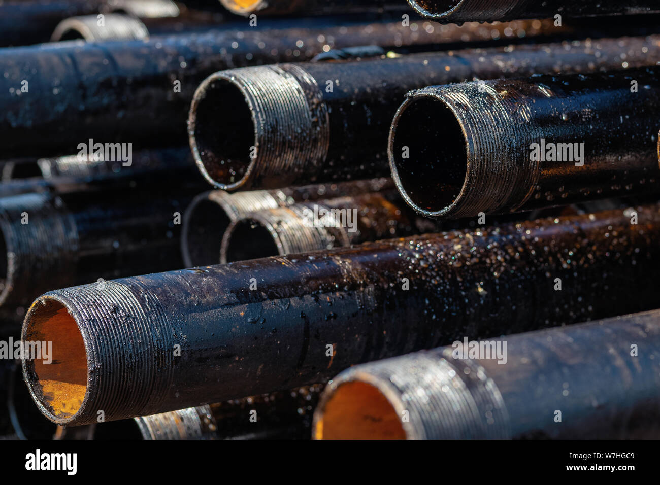 Vista di foratura involucro di tubazioni e tubi impilati in cantiere aperto del petrolio e del gas il magazzino. Foto Stock