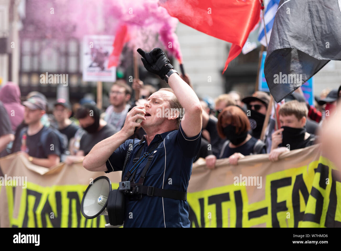 Anti manifestanti fascista in opposizione al Free Tommy Robinson rally di protesta a Londra, Regno Unito. Leader cantando in megafono. Il fumo proveniente da flare Foto Stock