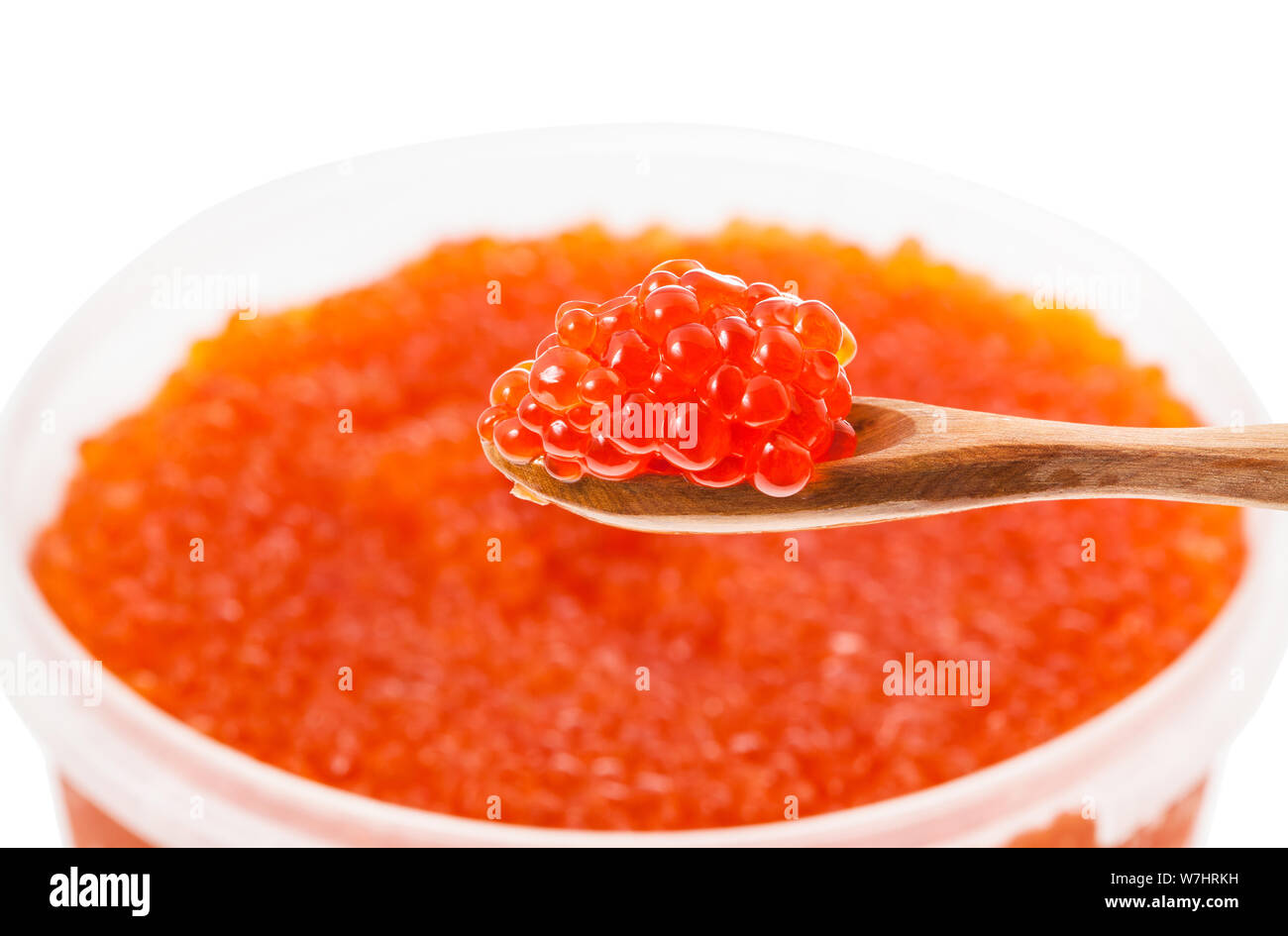 Piccolo cucchiaio di legno salate con il russo caviale rosso di salmone rosso pesce con sfocate contenitore in plastica con red roe di salmone rosa su sfondo iso Foto Stock