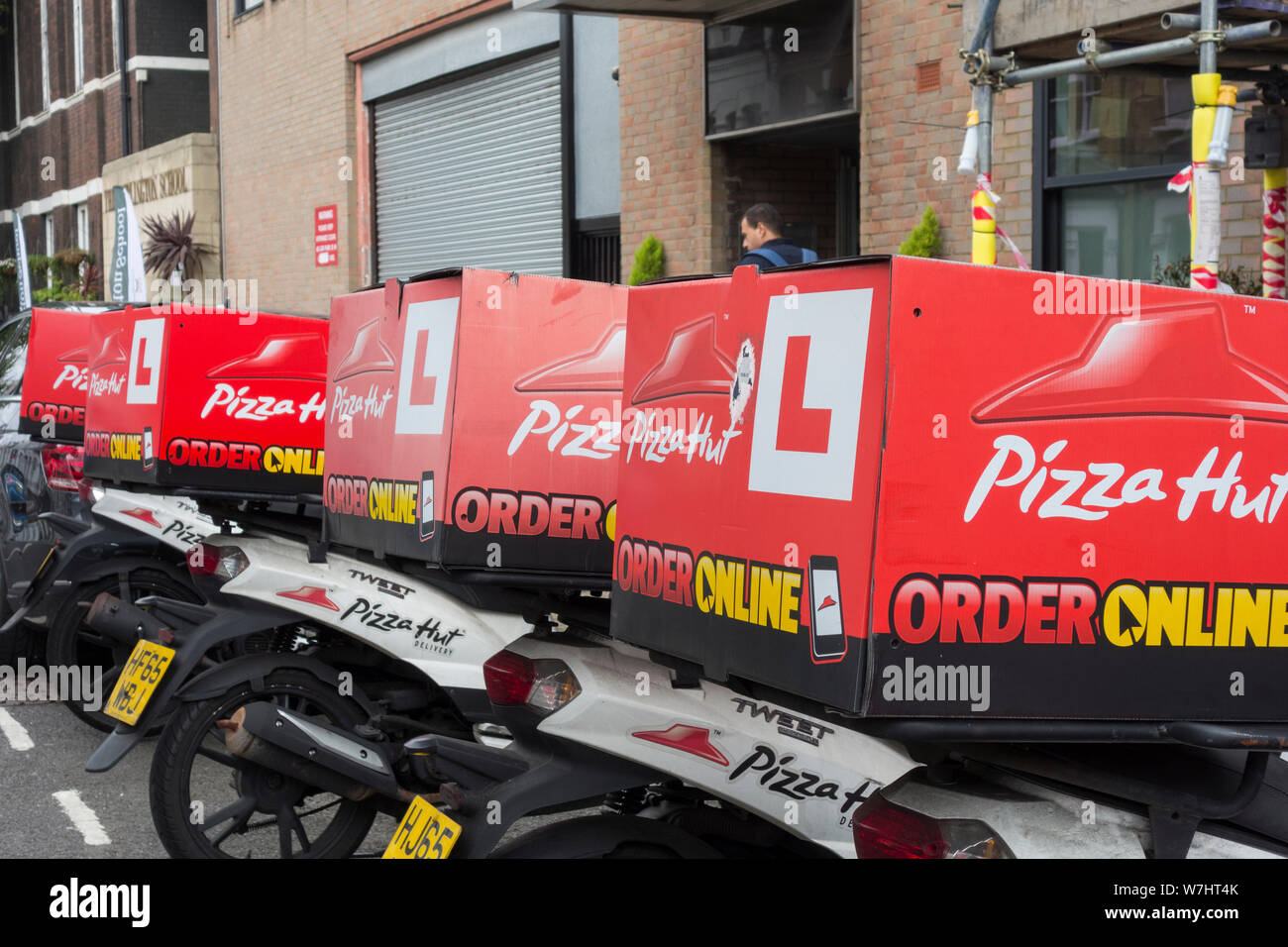 Una fila di Pizza Hut scooter parcheggiato al di fuori di uno dei suoi negozi su Fulham Road, Fulham, Londra, Regno Unito Foto Stock