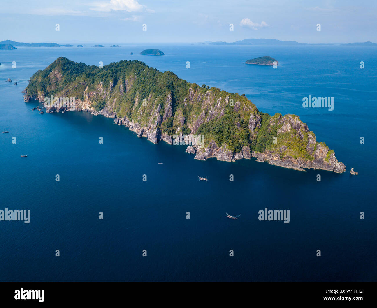 Antenna fuco vista di un gran numero di imbarcazioni di pesca artigianale lavorando fuori una lunga isola tropicale in un oceano tropicale Foto Stock