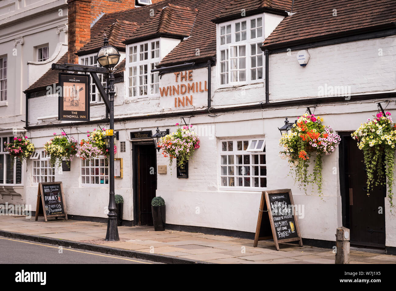 Caffè e ristoranti: una vista esterna del Windmill Inn con appeso un segno e cesti di fiori e un vecchio lampione esterno. Foto Stock
