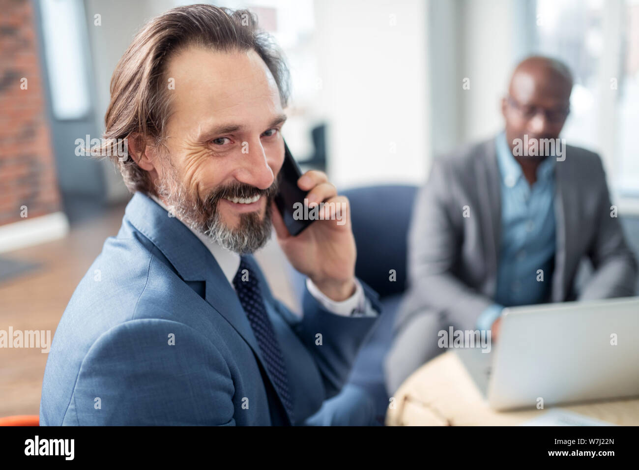 Imprenditore sentirsi felice che riceve la chiamata dalla moglie durante il lavoro Foto Stock