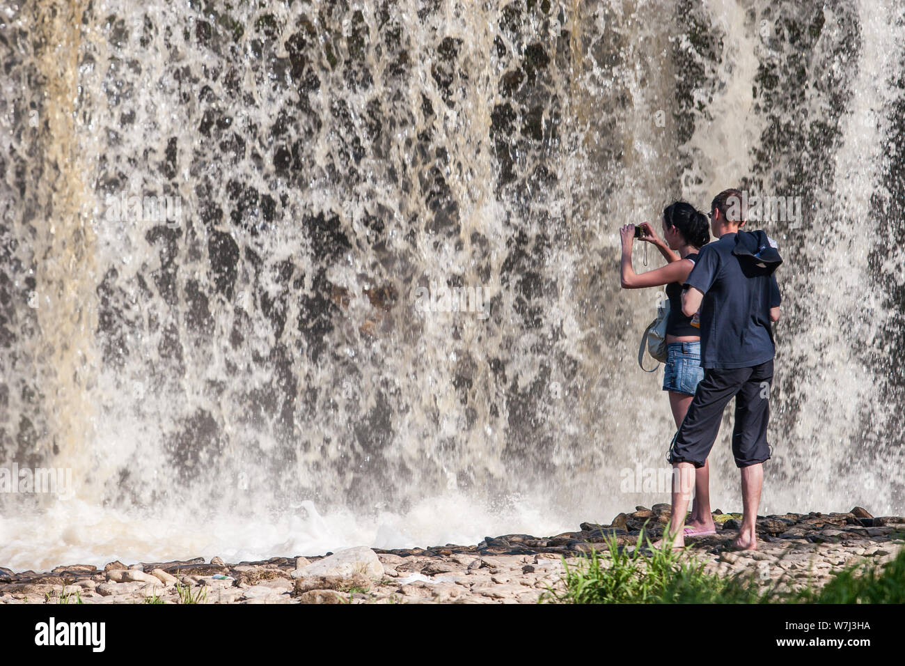 I turisti scattare foto della cascata molto vicino. Molta acqua. Potente flusso. L'acqua è sfocata. Foto Stock