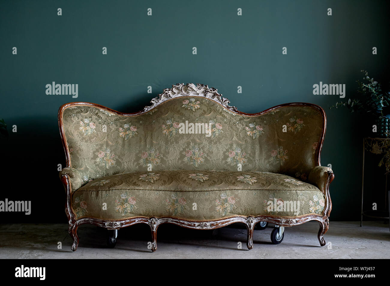 Vecchio divano con un forte legno, tessuto imbottito. Contro la parete verde.retrò interno Foto Stock