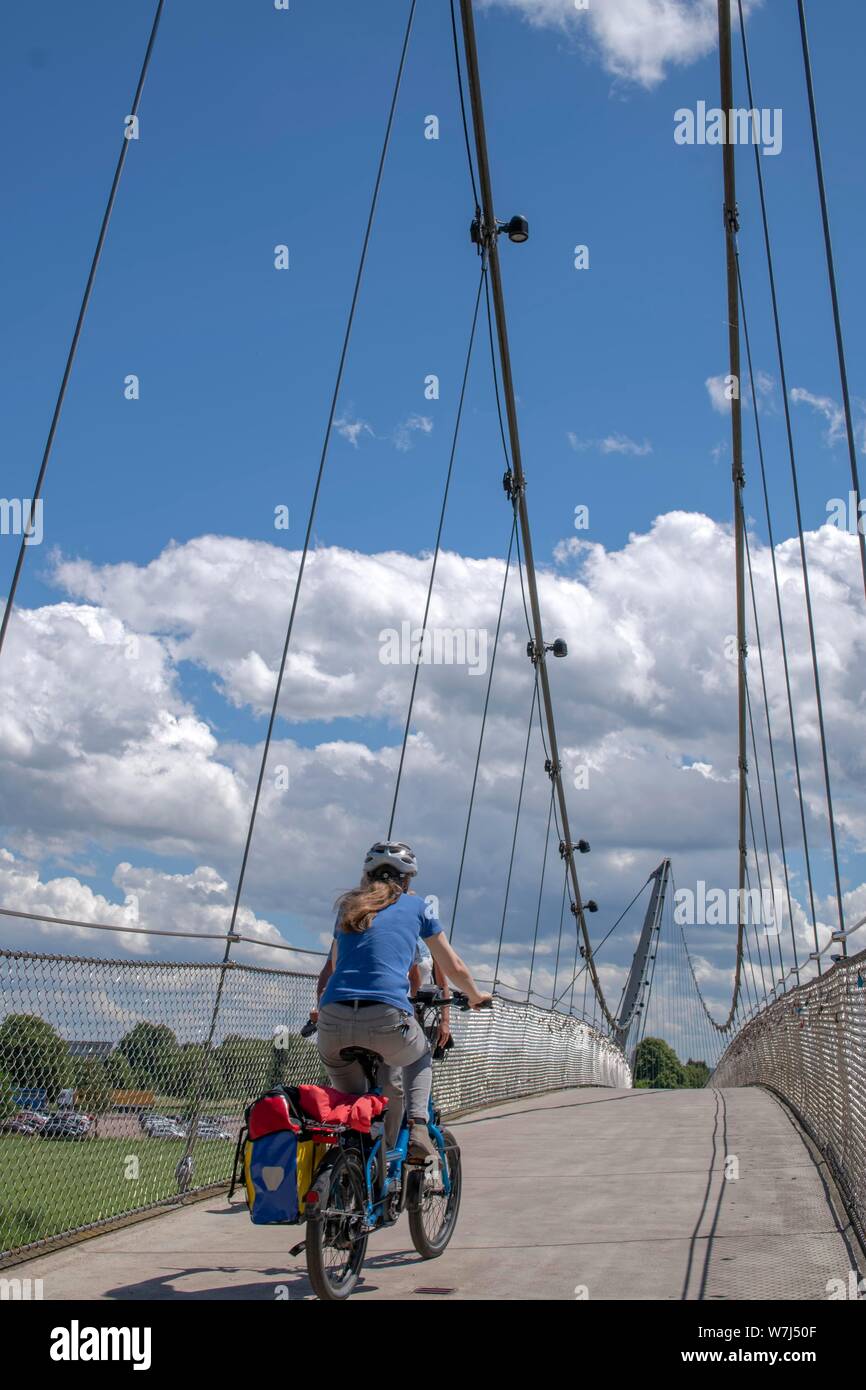 Ciclista a cavallo su un ponte sospeso, Minden, Renania settentrionale-Vestfalia, Germania Foto Stock