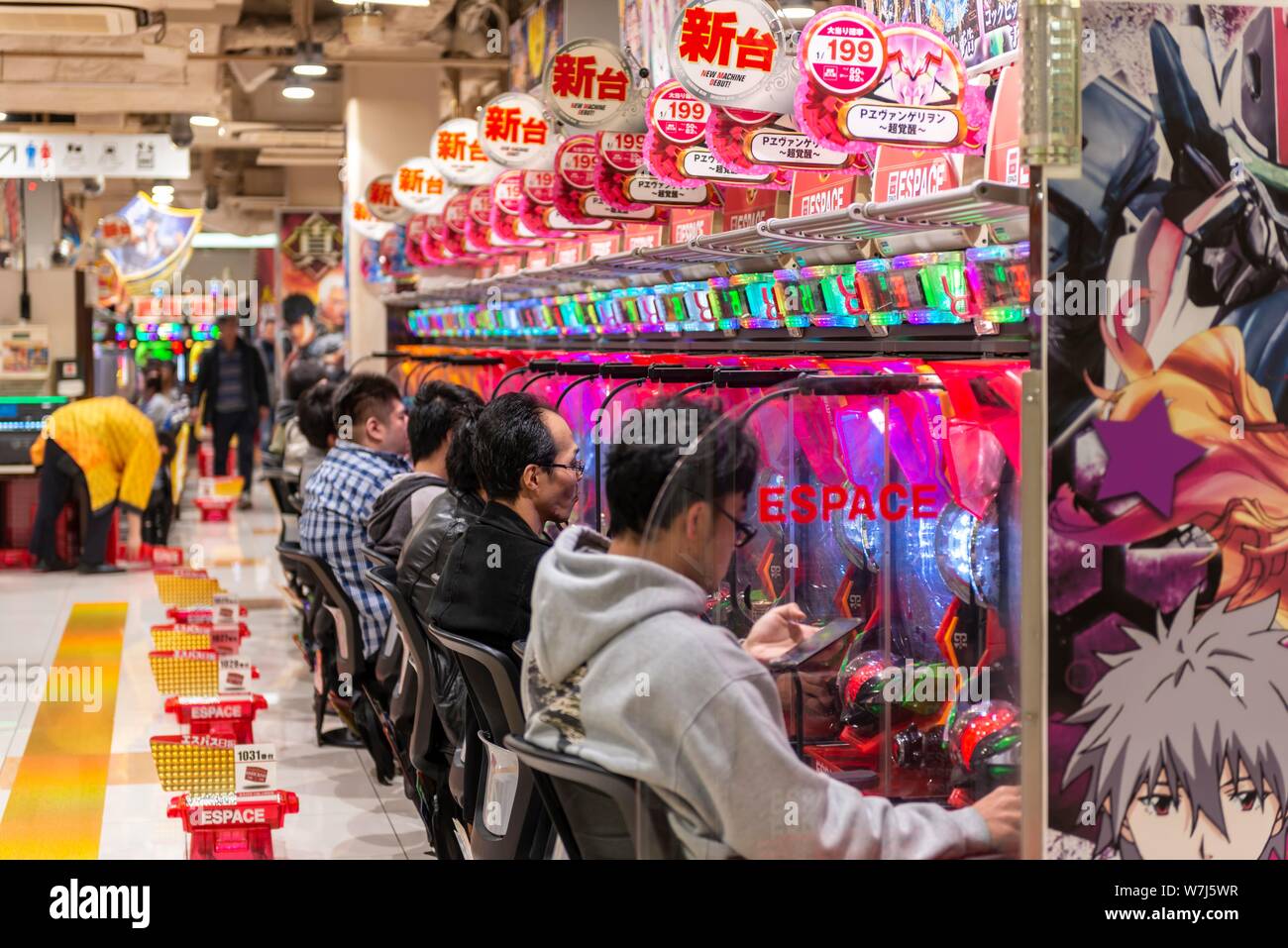 I giocatori si siedono a macchine di scanalatura in un casinò, Tokyo, Giappone Foto Stock