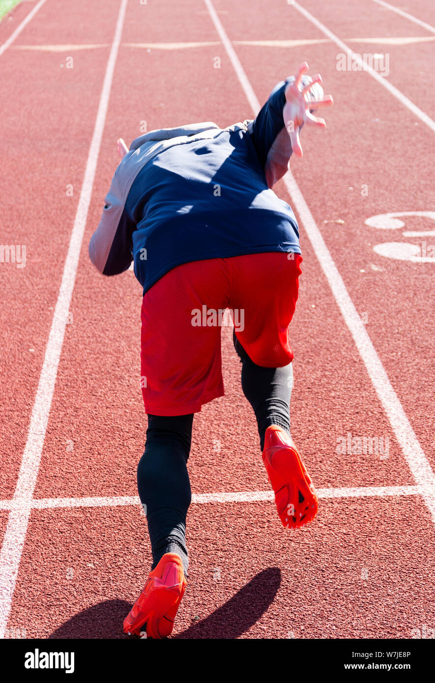 Un liceo sprinter è mettere in pratica l'inizio della sua corsa in inverno su una traccia. La foto è stata scattata da dietro l'atleta. Foto Stock