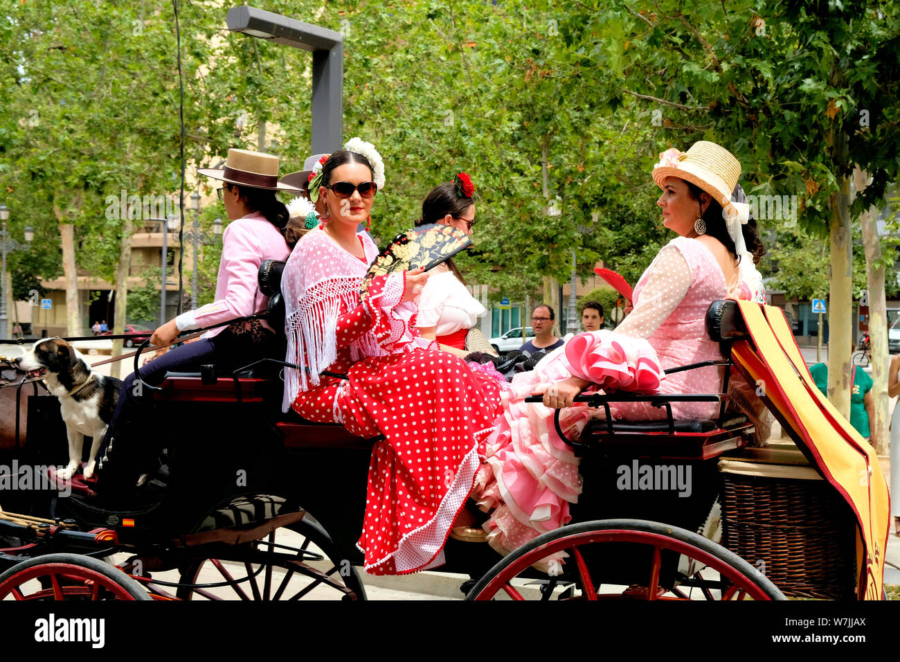 Le donne nel tradizionale costume spagnolo sulla cima di un carro trainato da cavalli (enganche), parte del Corpus Domini celebrazione in Granada, Spagna. Foto Stock