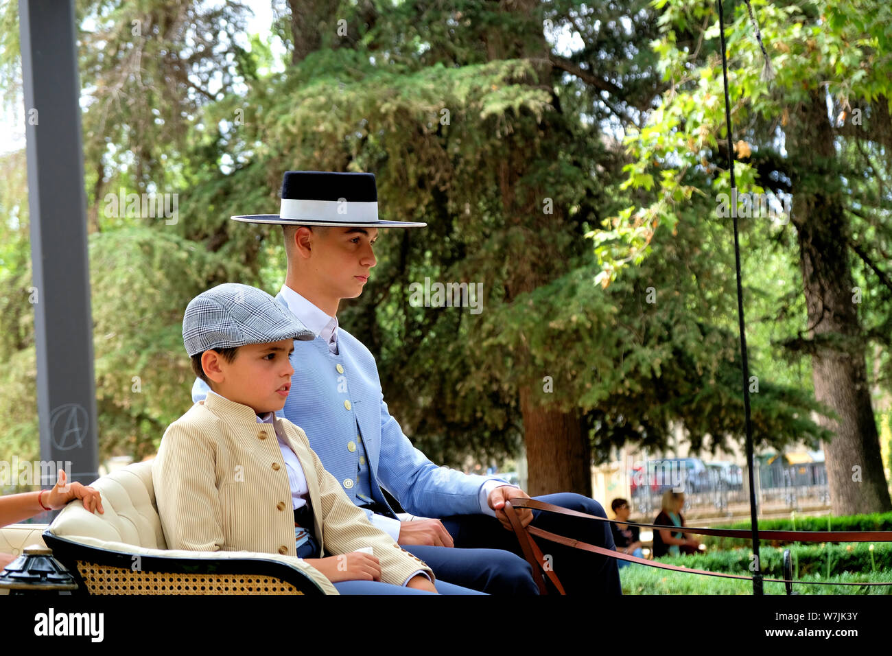 Due ragazzi in abito tradizionale azienda regna sulla cima di un carrozze trainate da cavalli (enganche), parte del Corpus Domini celebrazione in Granada, Spagna. Foto Stock