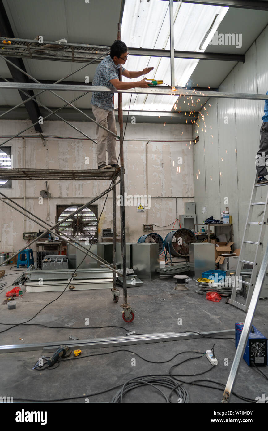 Uomo asiatico in piedi su ponteggi durante la saldatura vicino Shanghai, Cina Foto Stock