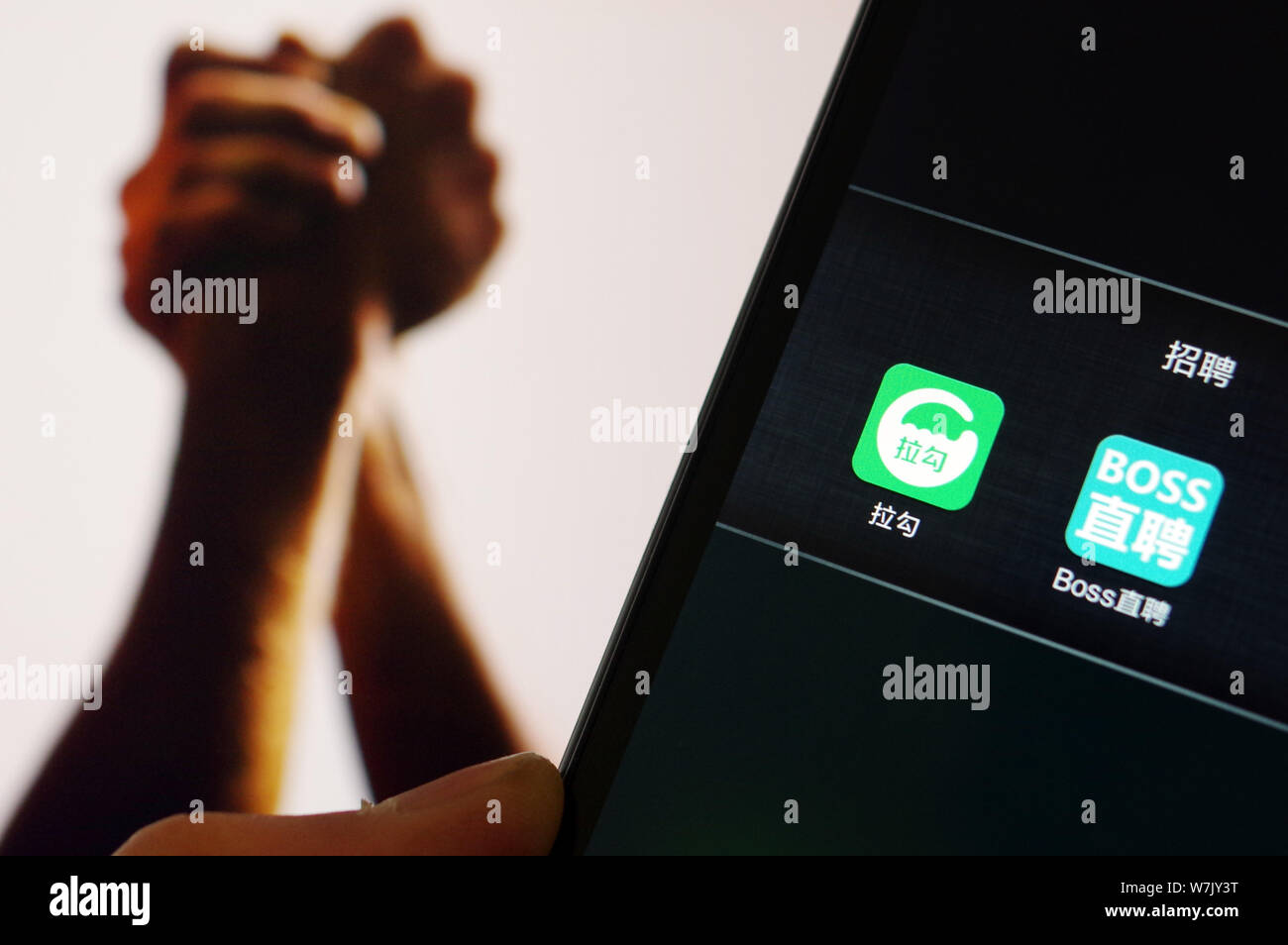 --FILE--un cinese mobilephone utente mostra le icone di Lagou, sinistra, un sito web specializzato in lavori nella tecnologia e nei settori di ingegneria e borchia Foto Stock