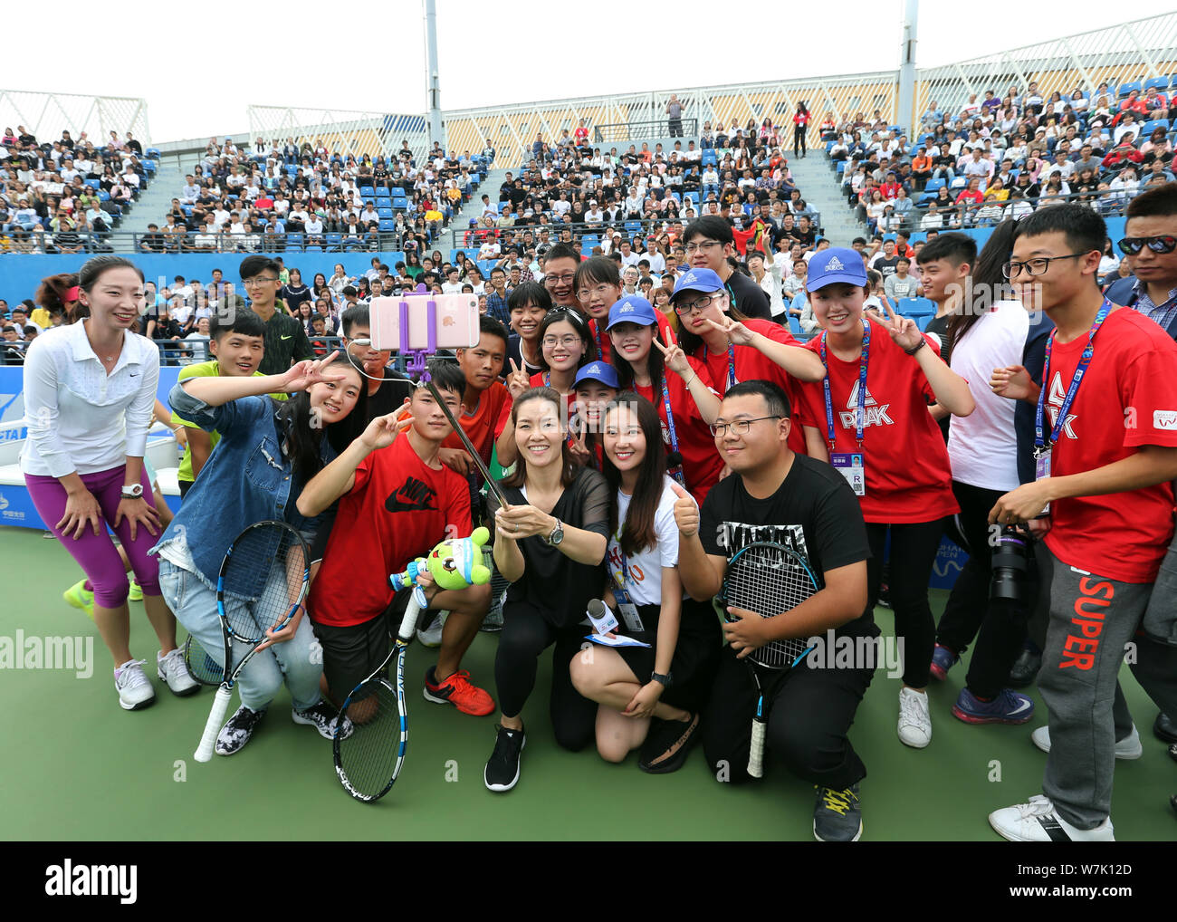 Due cinesi-time Grand Slam champion Li Na, centro pone per selfies con i giovani giocatori, volontari e tifosi durante il 2017 WTA Wuhan aprire il progetto e Foto Stock