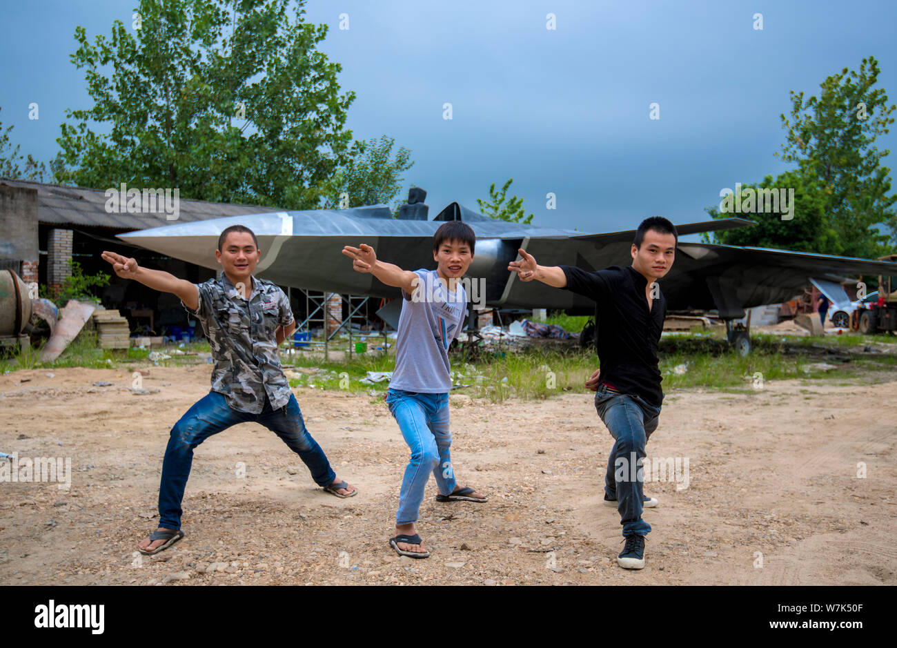 (Da sinistra) Cinese gli appassionati di militari Gu Chunlin, Huang Aibo e Wan Li posano con il modello a grandezza del J-20 Stealth Fighter Aircraft di lombata Foto Stock