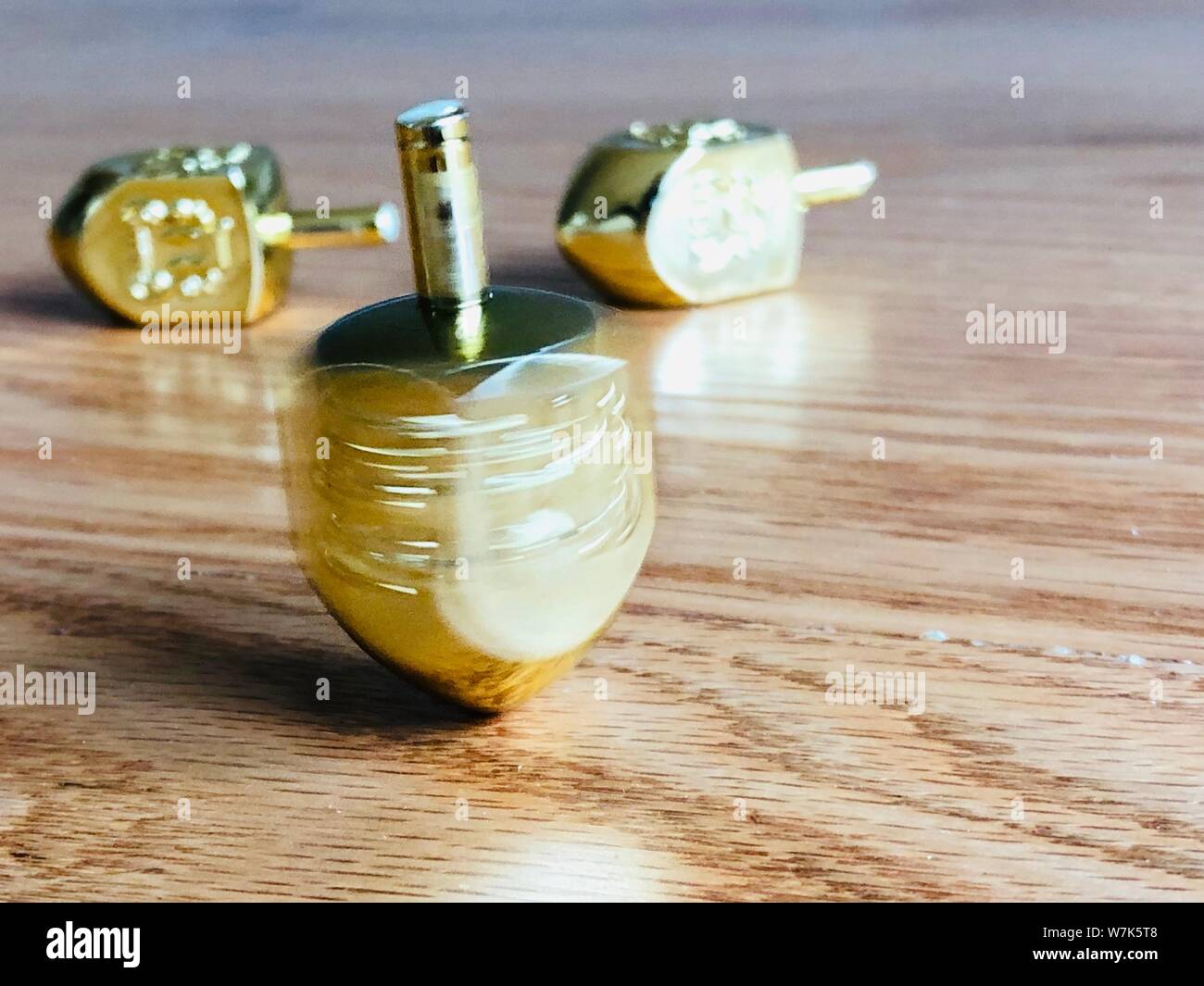Oro filatura Dreidel alto su un pavimento di legno Hanukkah giocattolo tradizionale festa ebraica Foto Stock