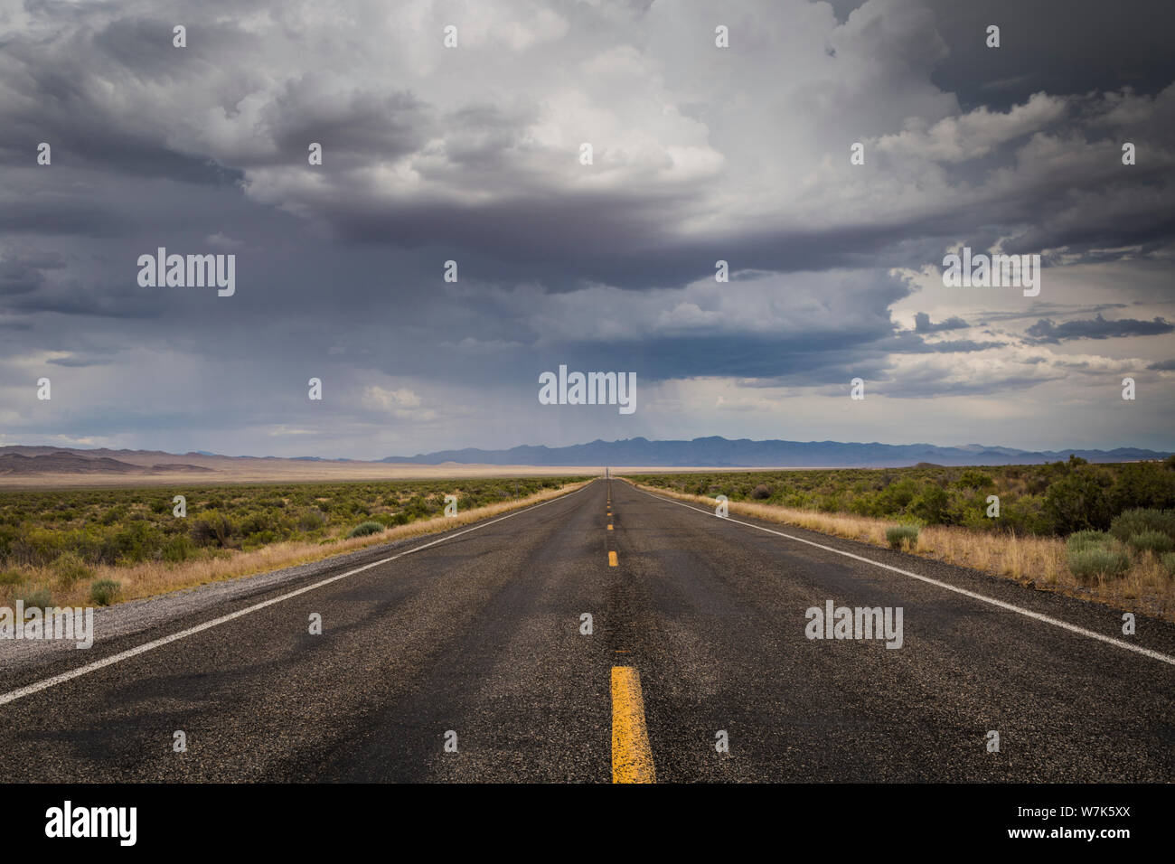 Le linee gialle di due corsie, US Highway 50, sotto il cielo nuvoloso al centro dell'alto deserto presso la Utah Nevada sul confine di un arretramento di estate Foto Stock
