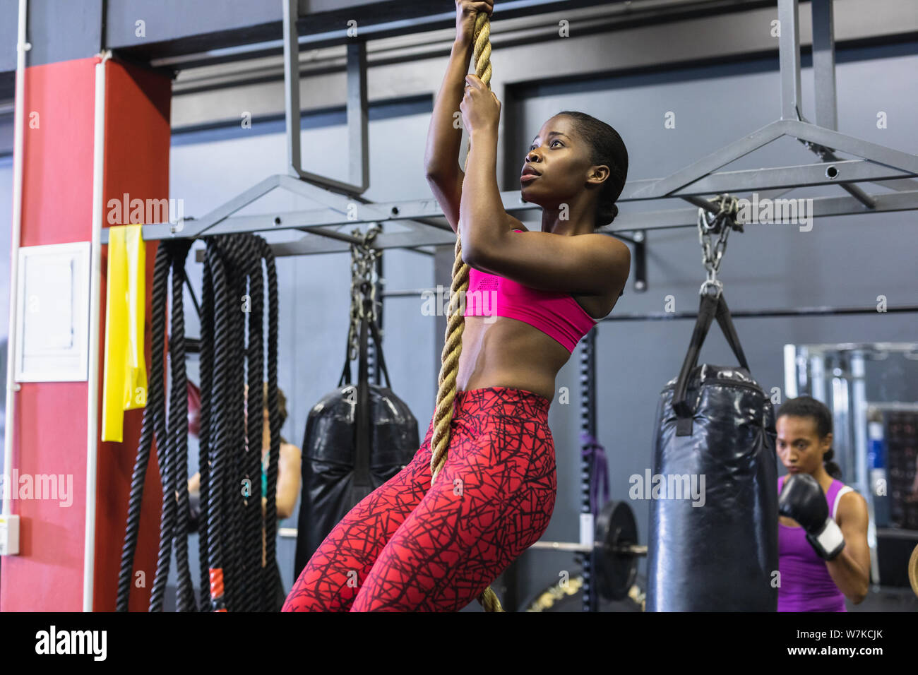 Femmina arrampicata atletica una corda nel centro fitness Foto Stock