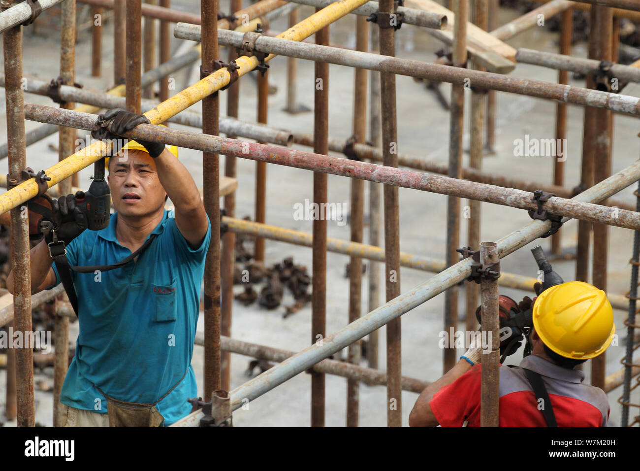 --FILE--cinese lavoratori migranti costruire impalcature presso il cantiere per la costruzione di immobili residenziali progetto nella città di Xuchang, centrale della Cina di Henan p Foto Stock