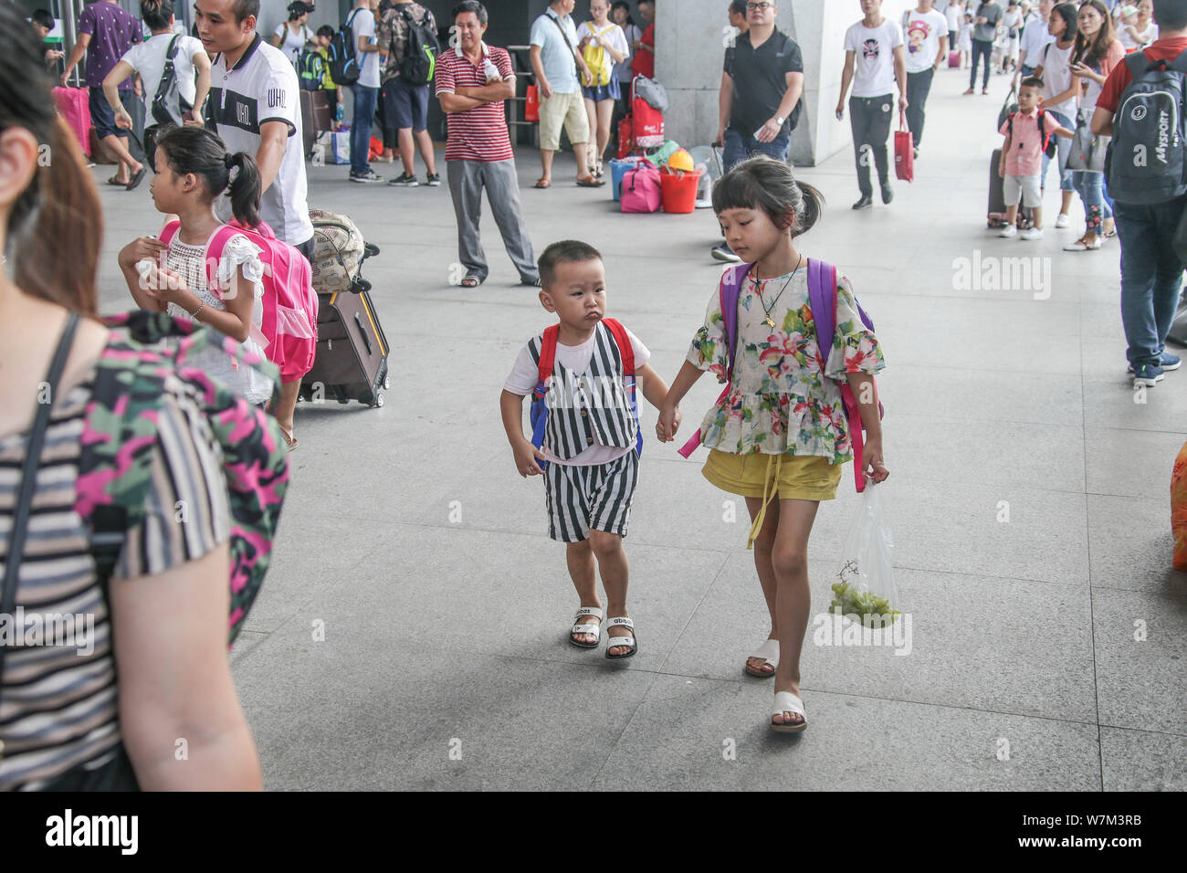 Una sinistra-dietro la ragazza e suo fratello sono ritratte dopo la separazione con i loro genitori a Quanzhou Stazione Ferroviaria di Quanzhou city, a sud-est della Cina di Fu Foto Stock