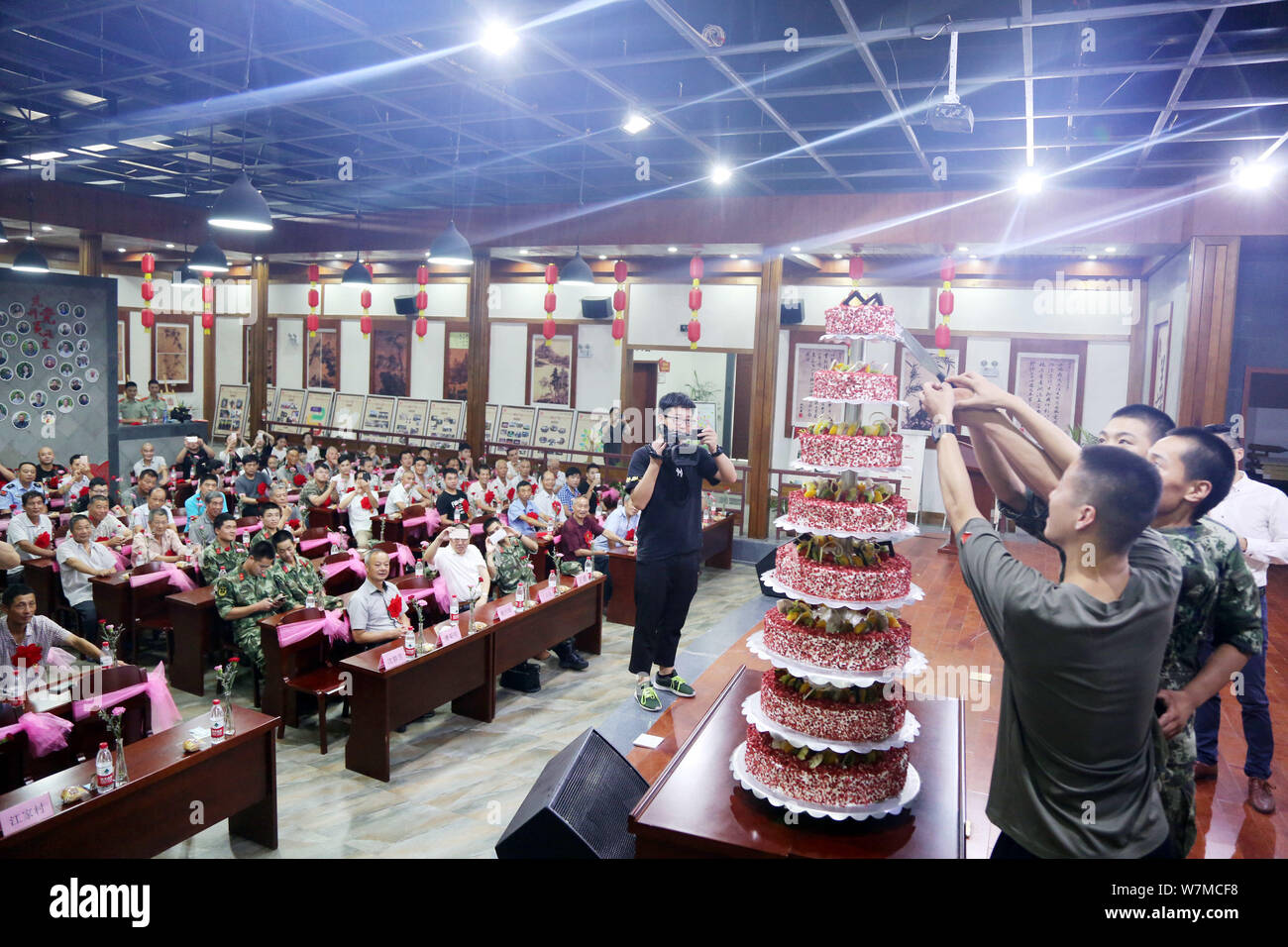 Veterani tagliare un otto-tiered torta presso un gruppo festa di compleanno per i veterani per contrassegnare il novantesimo anniversario del militare cinese la fondazione (1 Agosto) in Foto Stock