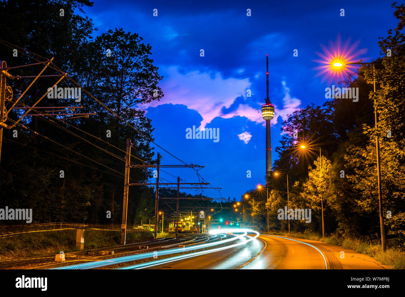 Germania, famoso punto di riferimento della città di Stoccarda la torre della televisione, chiamato fernsehturm di notte con il traffico sfocata durante una tempesta elettrica è in arrivo Foto Stock