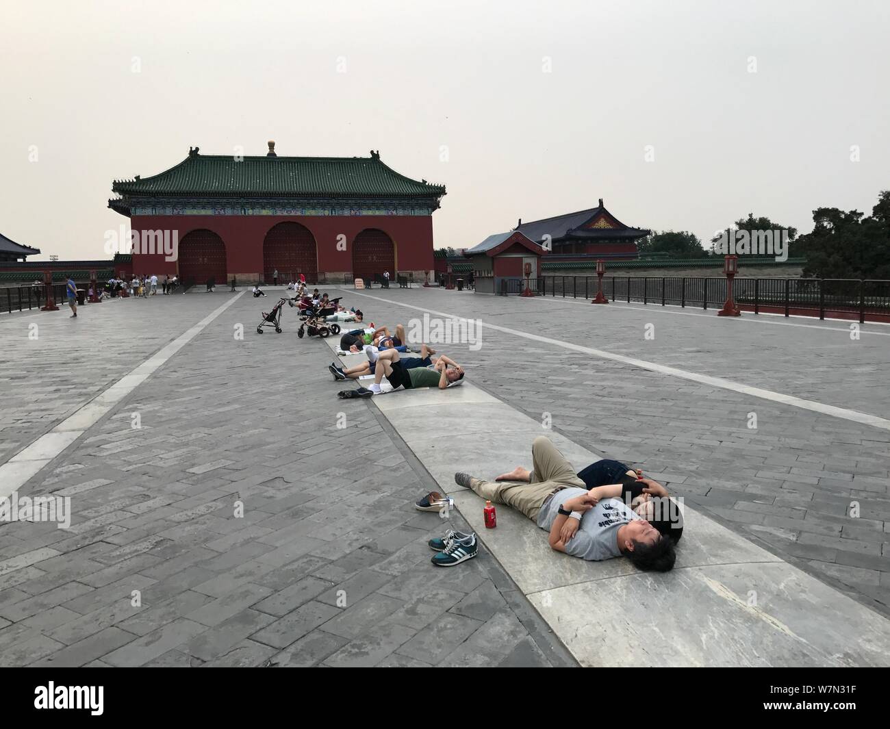 Visitatori cinesi giacciono sul ponte Danbi nel Tempio del Cielo Park per alleviare il dolore in una torrida giornata d'estate a Pechino in Cina, 2 luglio 2017. Danb Foto Stock