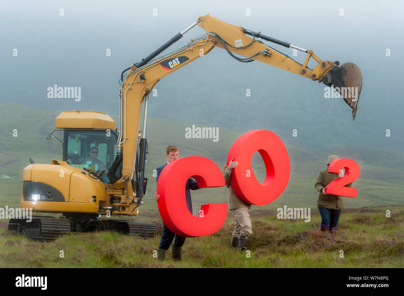 Persone azienda segni ortografia CO2, che rappresenta la cattura del carbonio per peatland sepoltura accanto todigging attrezzatura. Sutherland, Scozia, luglio 2012. Foto Stock