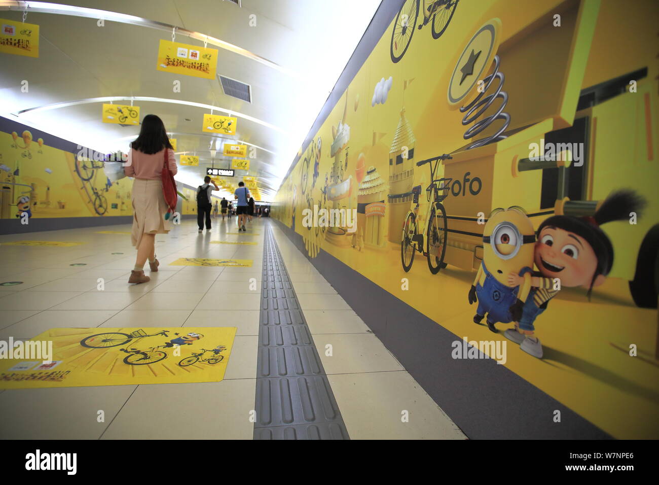 I pedoni a piedi passato una lunga 60 metri e cartello di tirapiedi in tema di biciclette cinesi di bike sharing service ofo promuovere il film 'Despicable Me 3' a Foto Stock