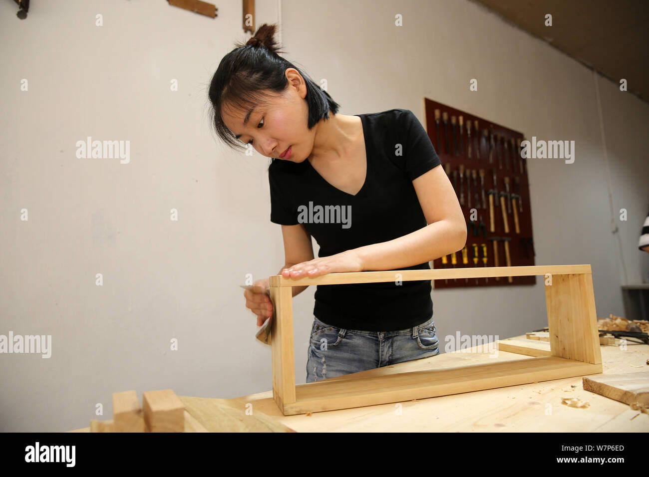Un cliente impara a fare lavori in legno sotto l istruzione di 32-anno-vecchio artigiano cinese Zhang Jian, una volta white¨Ccollar lavoratore, in falegnameria e Foto Stock
