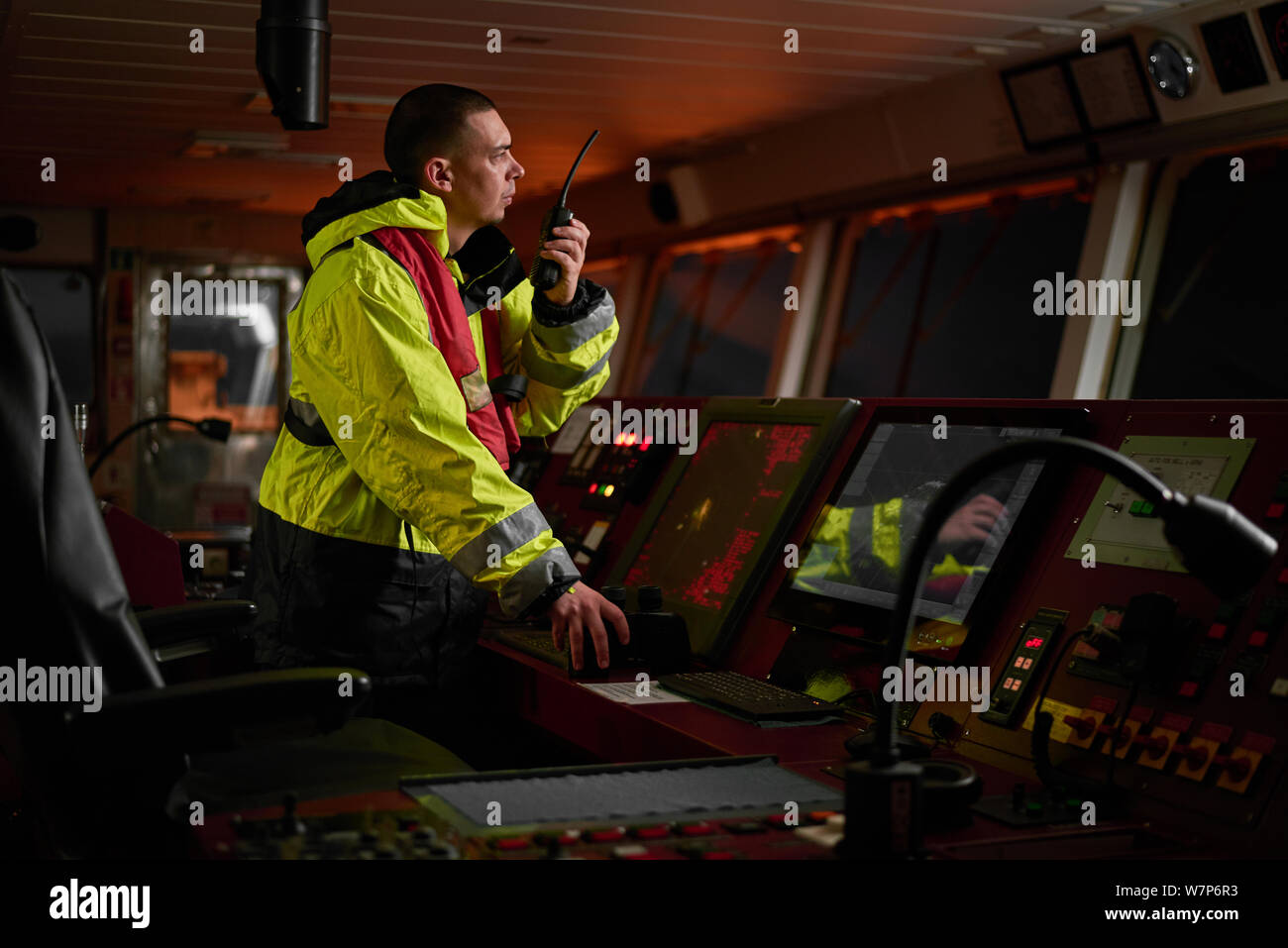 Navigator. pilota, capitano come parte dell equipaggio della nave di eseguire incarichi giornalieri con la radio VHF, binocolo, giornale di bordo, in piedi vicino a ECDIS e stazione radar Foto Stock