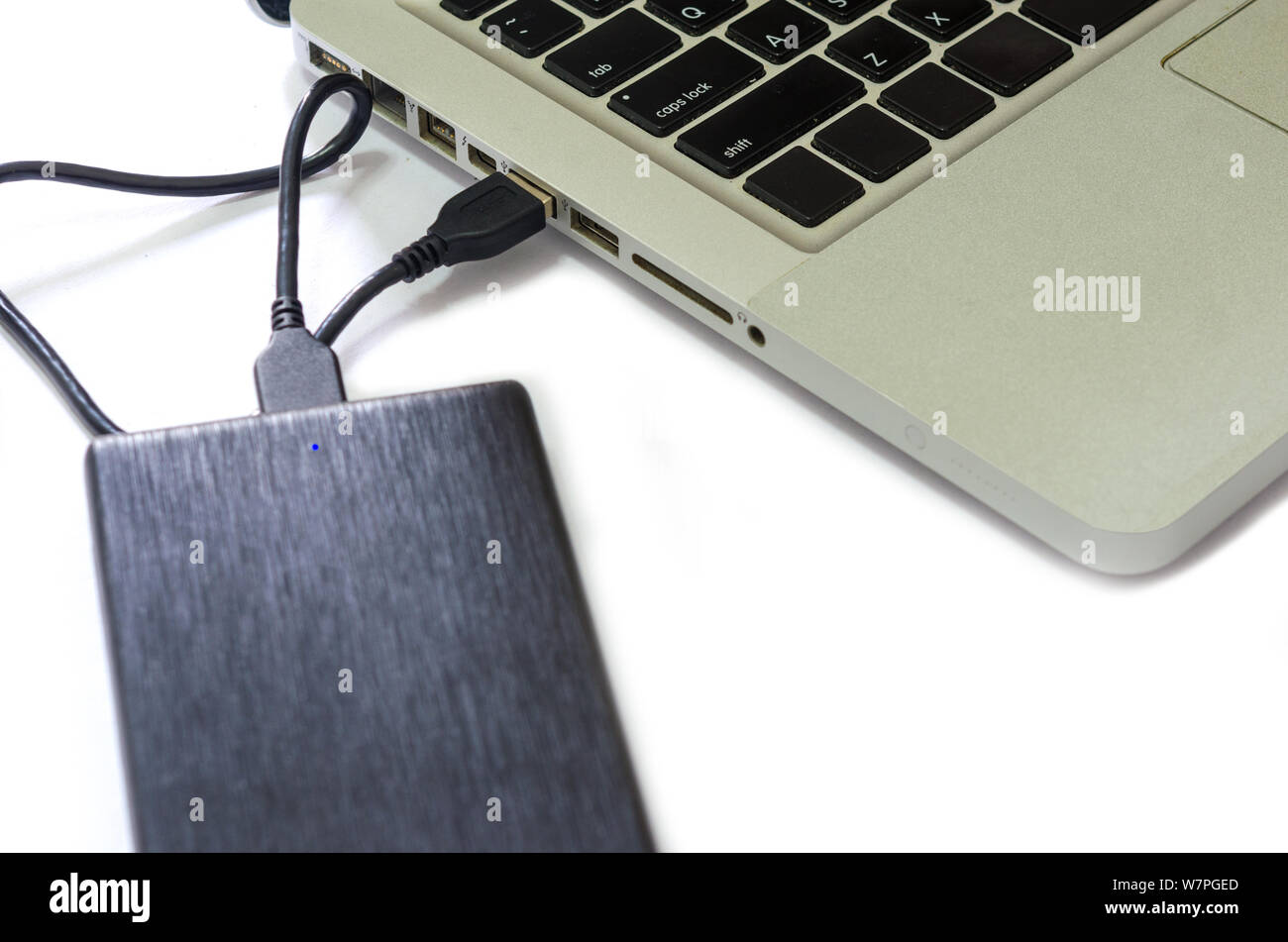 Disco rigido esterno collegare al computer portatile su uno sfondo bianco. Foto Stock