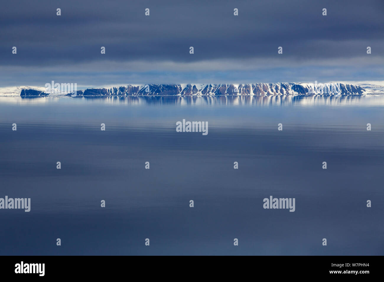 Le scogliere si riflette perfettamente in condizioni di mare calmo, Nordaustlandet, Svalbard, Norvegia Foto Stock