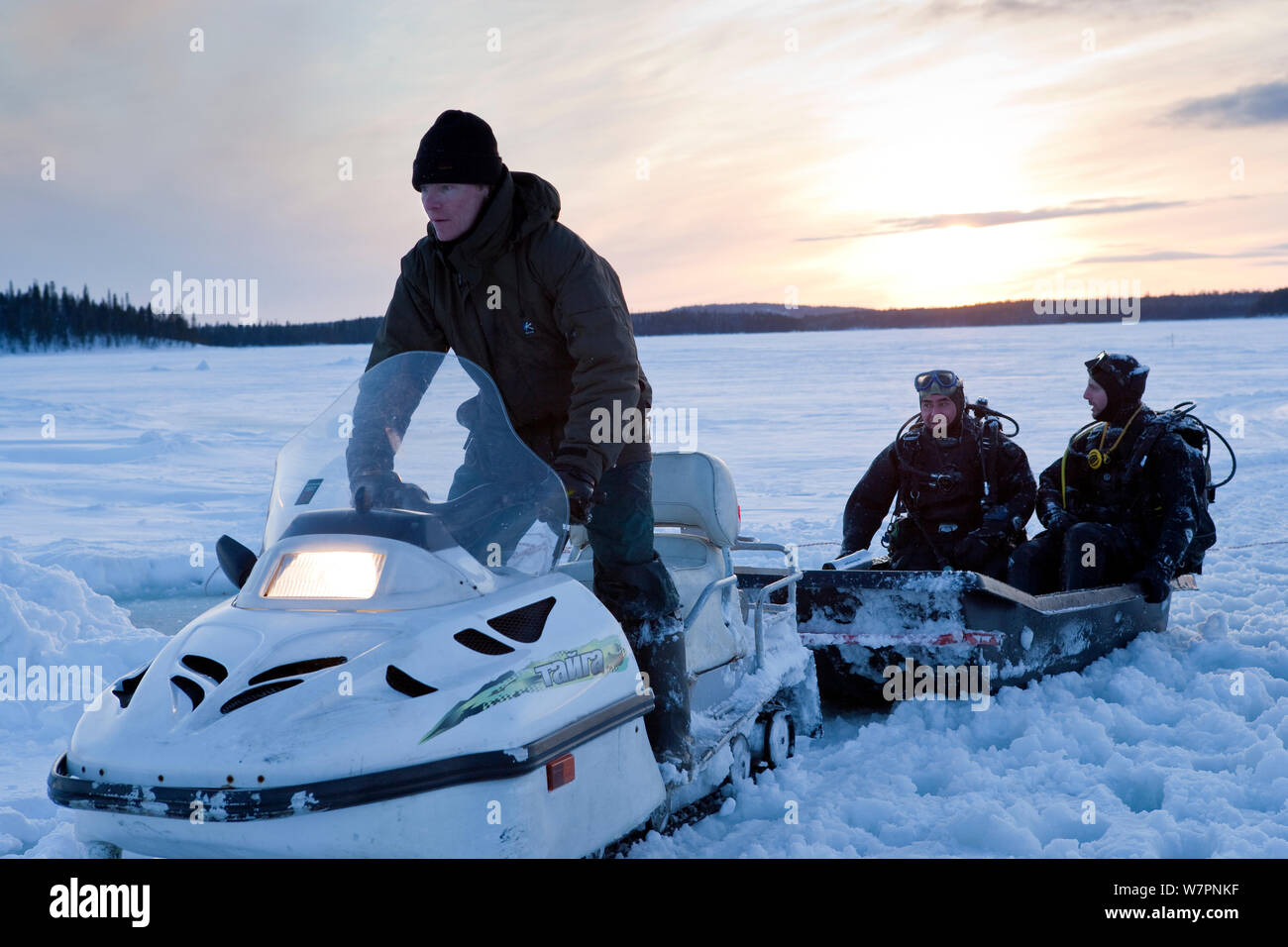 Due subacquei su una slitta trainata da ski-doo motoslitta per andare immersioni sotto il ghiaccio, Circolo Polare Artico Dive Center, Mare Bianco, Carelia, Russia settentrionale, Marzo 2010 Foto Stock