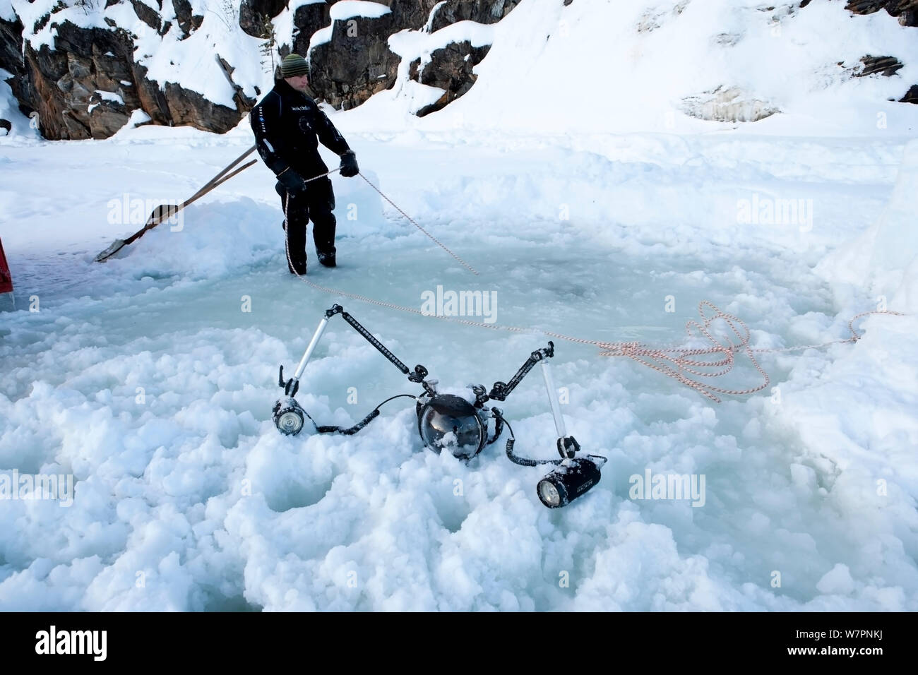 Fotocamera Subacquea alloggiamento e pulsa nella neve vicino al 'maina' le immersioni sotto il ghiaccio foro, con la persona che tiene la corda realizzando il contatto con i subacquei all'interno. Circolo polare artico Dive Center, Mare Bianco, Carelia, Russia settentrionale, Marzo 2010 Foto Stock