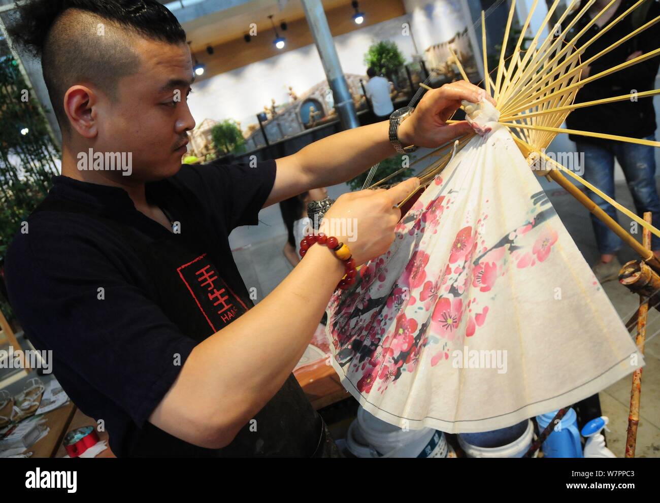 La settima generazione successore di Luzhou a olio di ombrello carta Yu Wanlun rende un olio ombrello della carta nel suo studio di Hangzhou, a est della Cina di Zhe Foto Stock