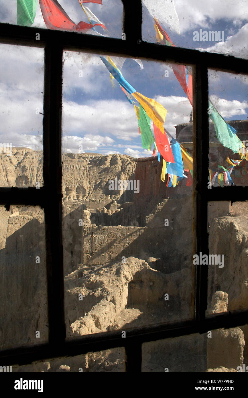 La preghiera buddista bandiere al di fuori del telaio della finestra a Tsaparang (talvolta noto come la mitica Shangri-la) fu la capitale dell'antico regno di Guge nella valle di Garuda, prefettura di Ngari, Tibet occidentale. Tsaparang è un enorme fortezza arroccata su una piramide di roccia a forma crescente circa 600 piedi (183m). Essa contiene numerose gallerie e grotte che sono state scavate nella roccia. Foto Stock