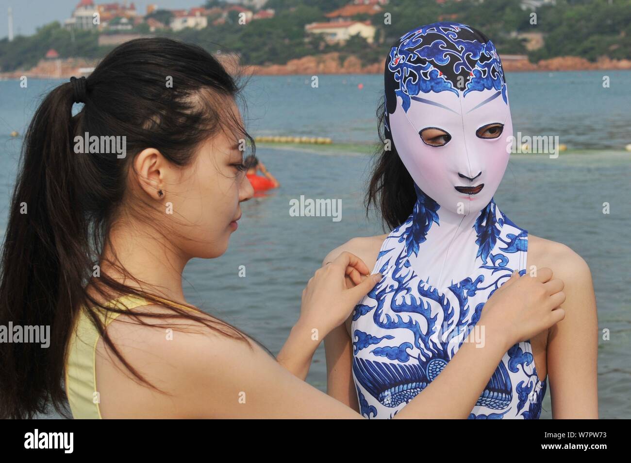 Un modello che indossa un costume da bagno facekini dotate di blu e bianco porcellana e ricamo è raffigurato in un villaggio su una spiaggia di Qingdao City, est della Cina di Shan Foto Stock