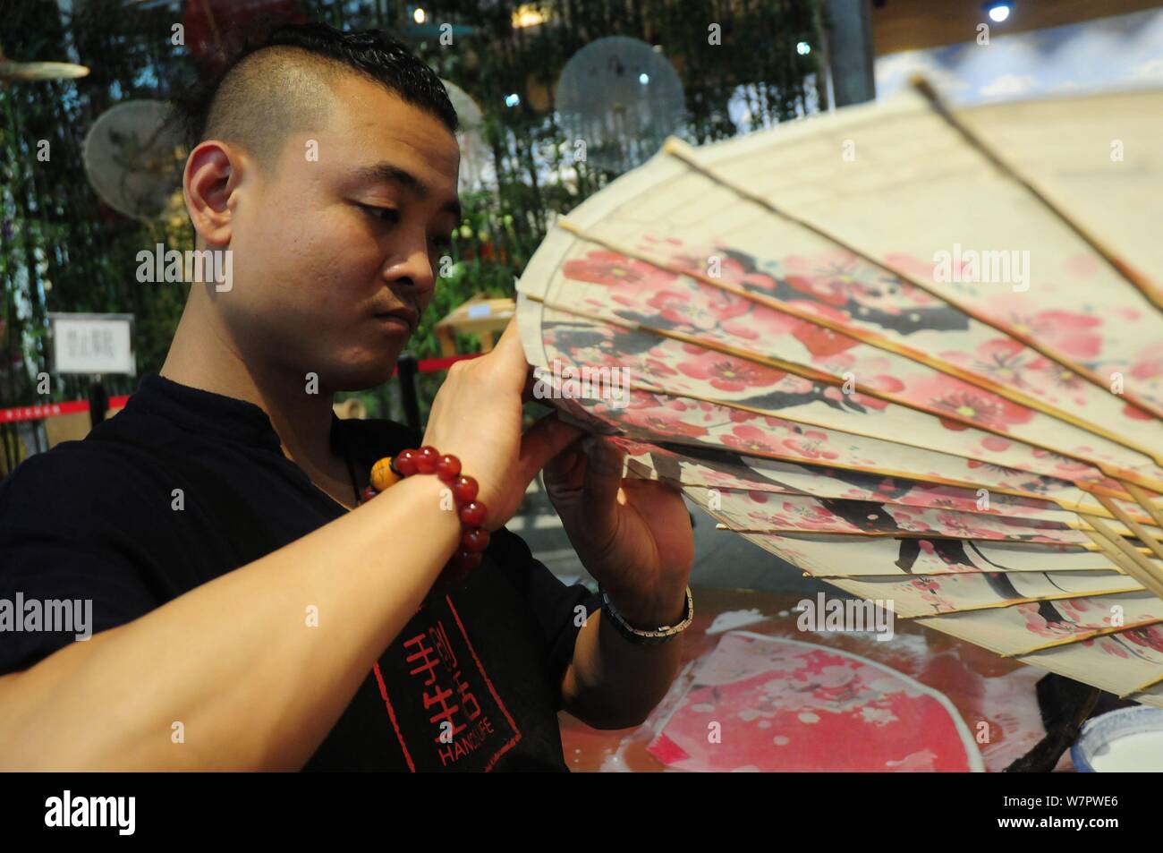 La settima generazione successore di Luzhou a olio di ombrello carta Yu Wanlun rende un olio ombrello della carta nel suo studio di Hangzhou, a est della Cina di Zhe Foto Stock