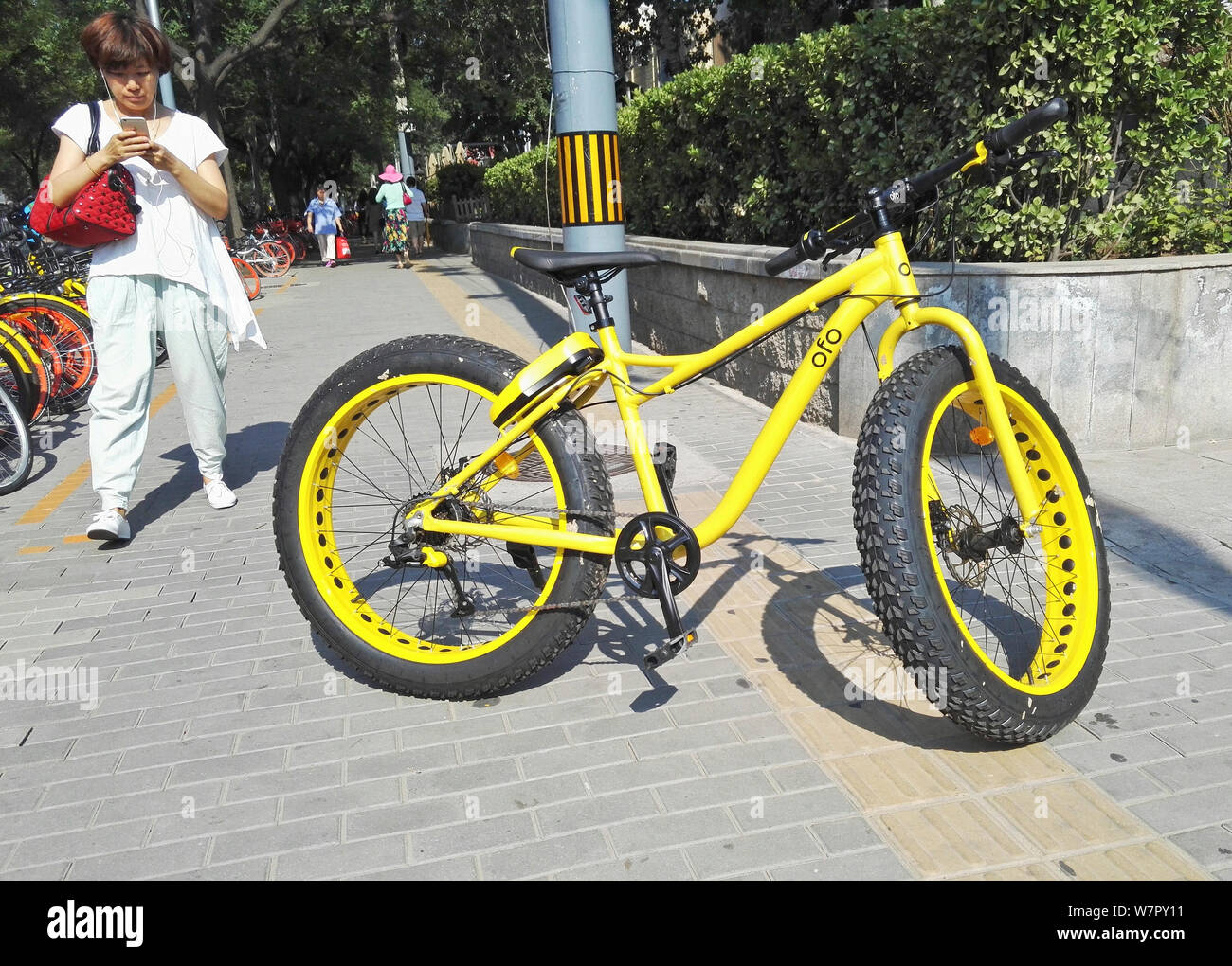 Un pedone prende le foto di un fatbike con pneumatici di grandi dimensioni, chiamato anche bici fat o fat-tire bike, Cinese di bike sharing service ofo, a Pechino, C Foto Stock