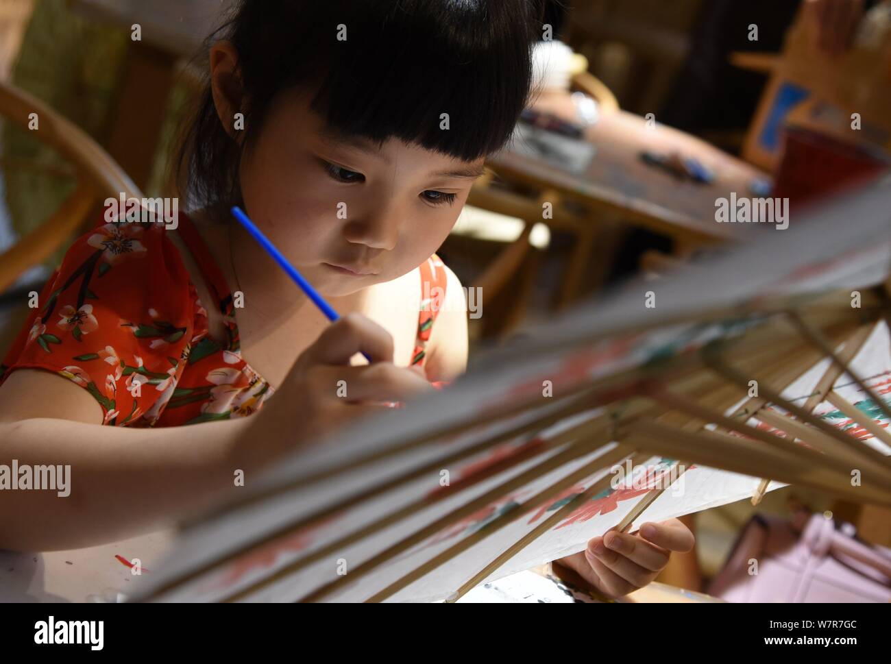 Un bambino vernici su un olio ombrello di carta al stuidio di Yu Wanlun, la settima generazione successore di Luzhou della carta olio ombrello, in Hangzhou Foto Stock