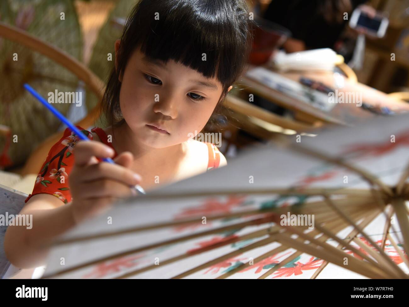 Un bambino vernici su un olio ombrello di carta al stuidio di Yu Wanlun, la settima generazione successore di Luzhou della carta olio ombrello, in Hangzhou Foto Stock