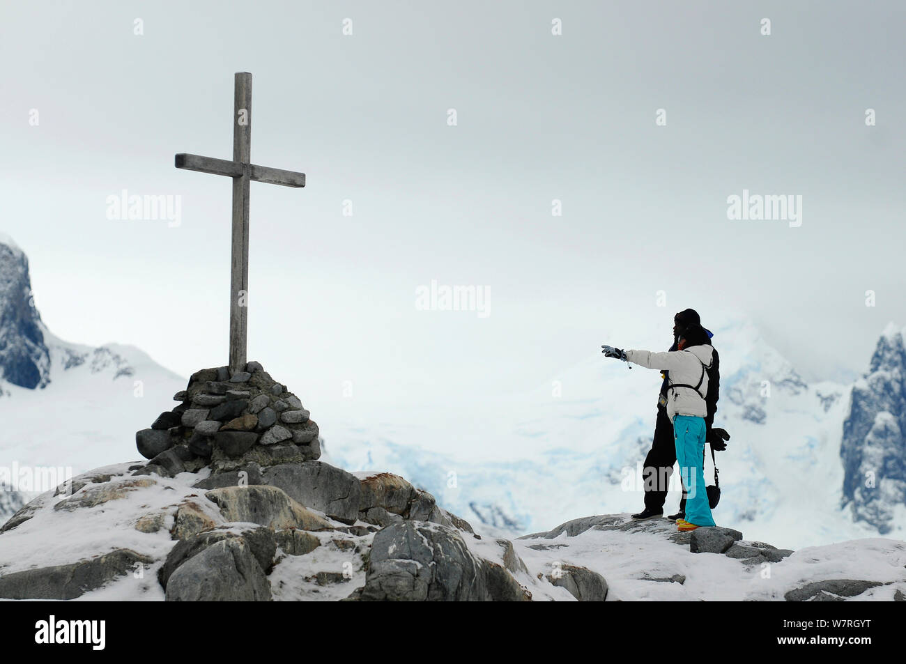 I turisti osservando una croce commemorativa in onore del British Antarctic Survey equipaggio, Ambrogio C Morgan, Kevin P Ockleton e John Coll morto nel 14 ago 1982. Petermann Island. Penisola antartica, Antartide Foto Stock