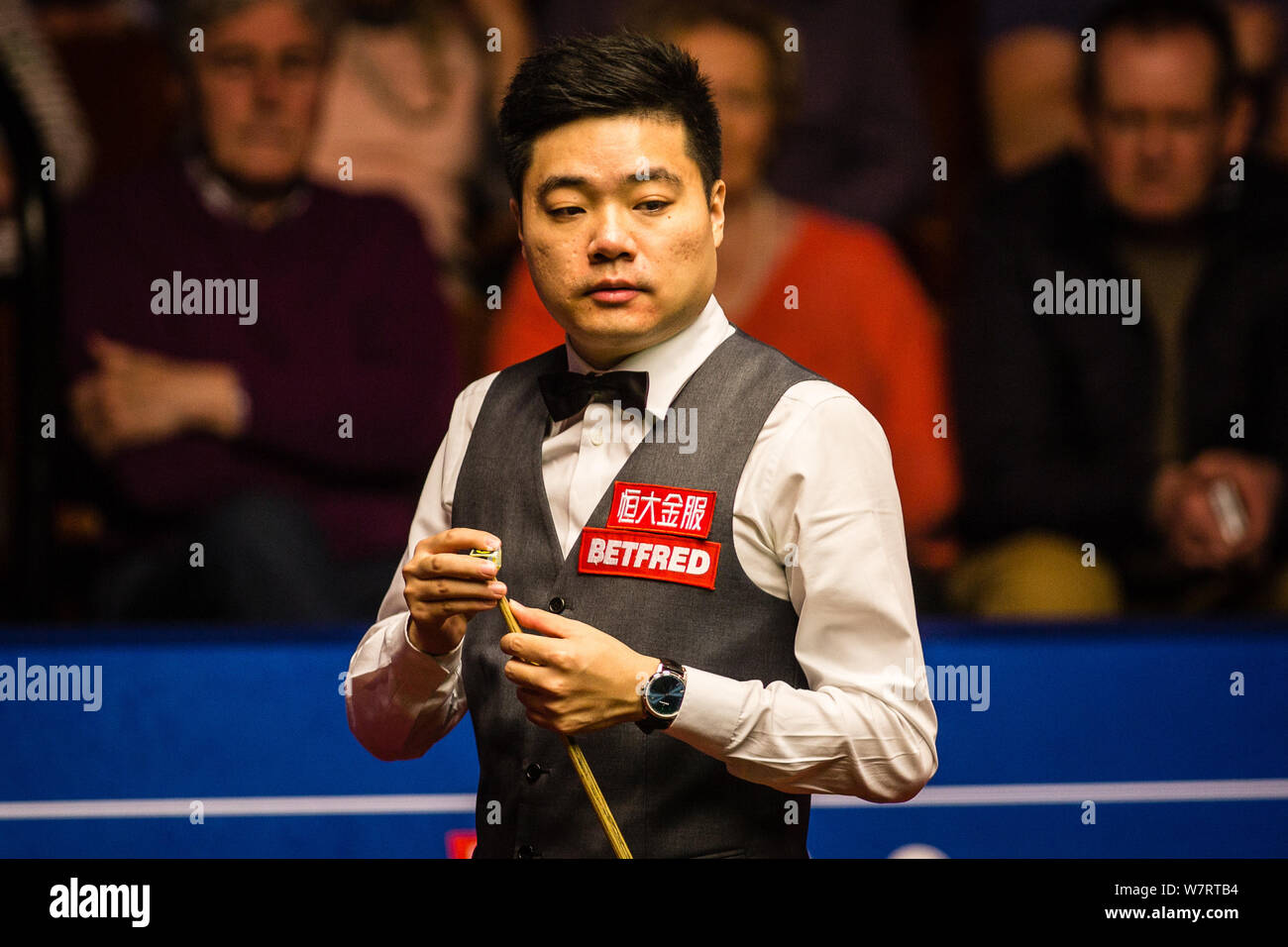 Ding Junhui della Cina i gessi spunto come egli ritiene che un colpo di Mark Selby dell'Inghilterra nell'ultima fase della loro semifinale partita durante il 2017 Betfred Foto Stock