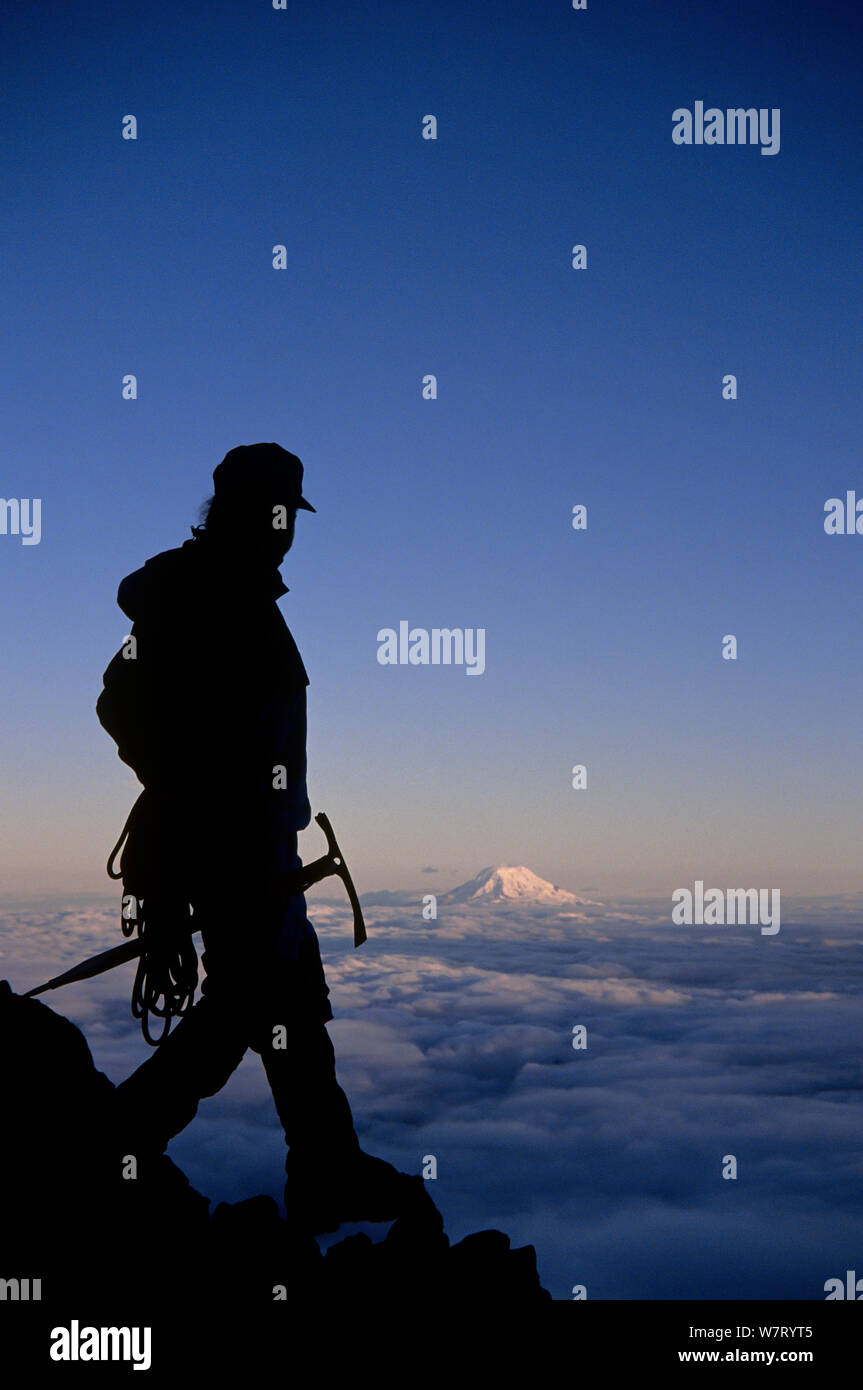 Scalatore sul Monte Rainier con il Monte Adams in distanza, il Parco Nazionale del Monte Rainier, Washington, Stati Uniti d'America. Modello rilasciato. Foto Stock