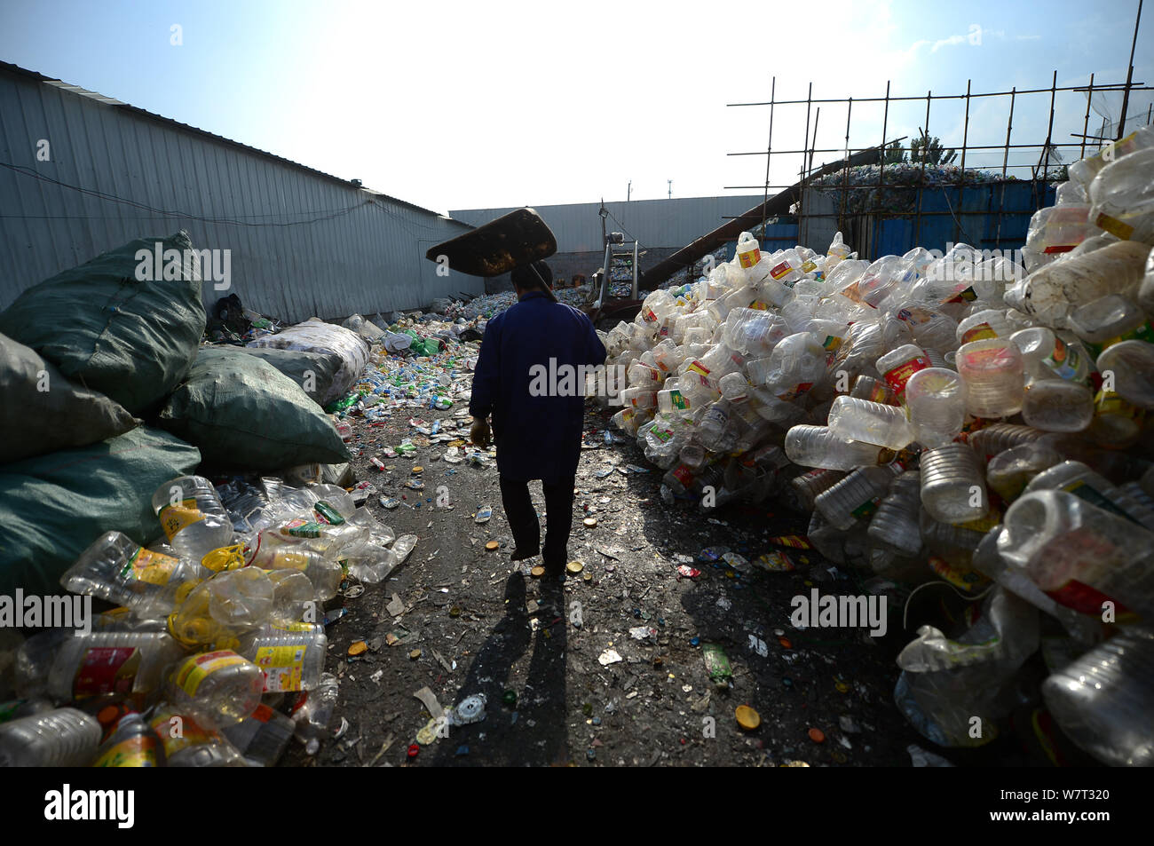 Un lavoratore cinese passeggiate attraverso alte pile di bottiglie di plastica a bottiglia di plastica riciclaggio, che ha intrappolato un uomo in Ji'nan città, Oriente Cina " Foto Stock