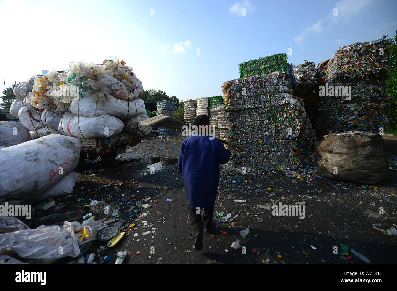 Un lavoratore cinese passeggiate attraverso alte pile di bottiglie di plastica a bottiglia di plastica riciclaggio, che ha intrappolato un uomo in Ji'nan città, Oriente Cina " Foto Stock