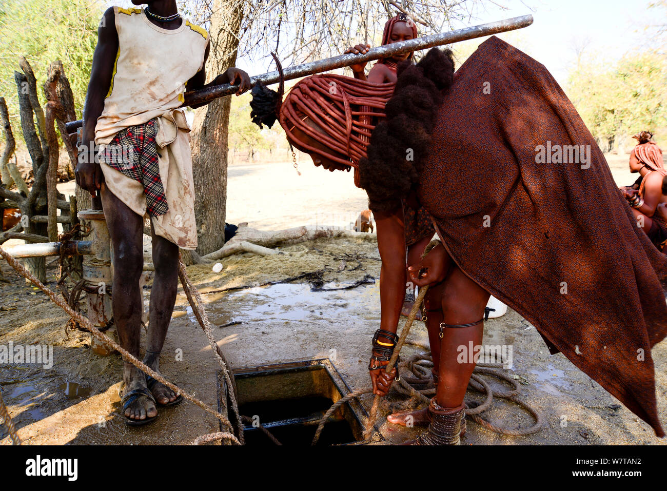 Himba donna con una corda tirando l'acqua da un pozzo e. Kaokoland, Namibia, settembre 2013. Foto Stock