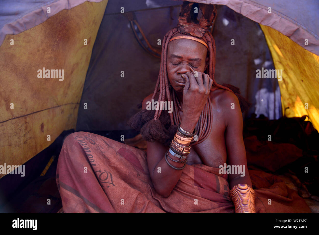 Donna Himba sbuffare nasale di tabacco da fiuto in tenda da campeggio e villaggio Himba, Kaokoland, Namibia, settembre 2013. Foto Stock