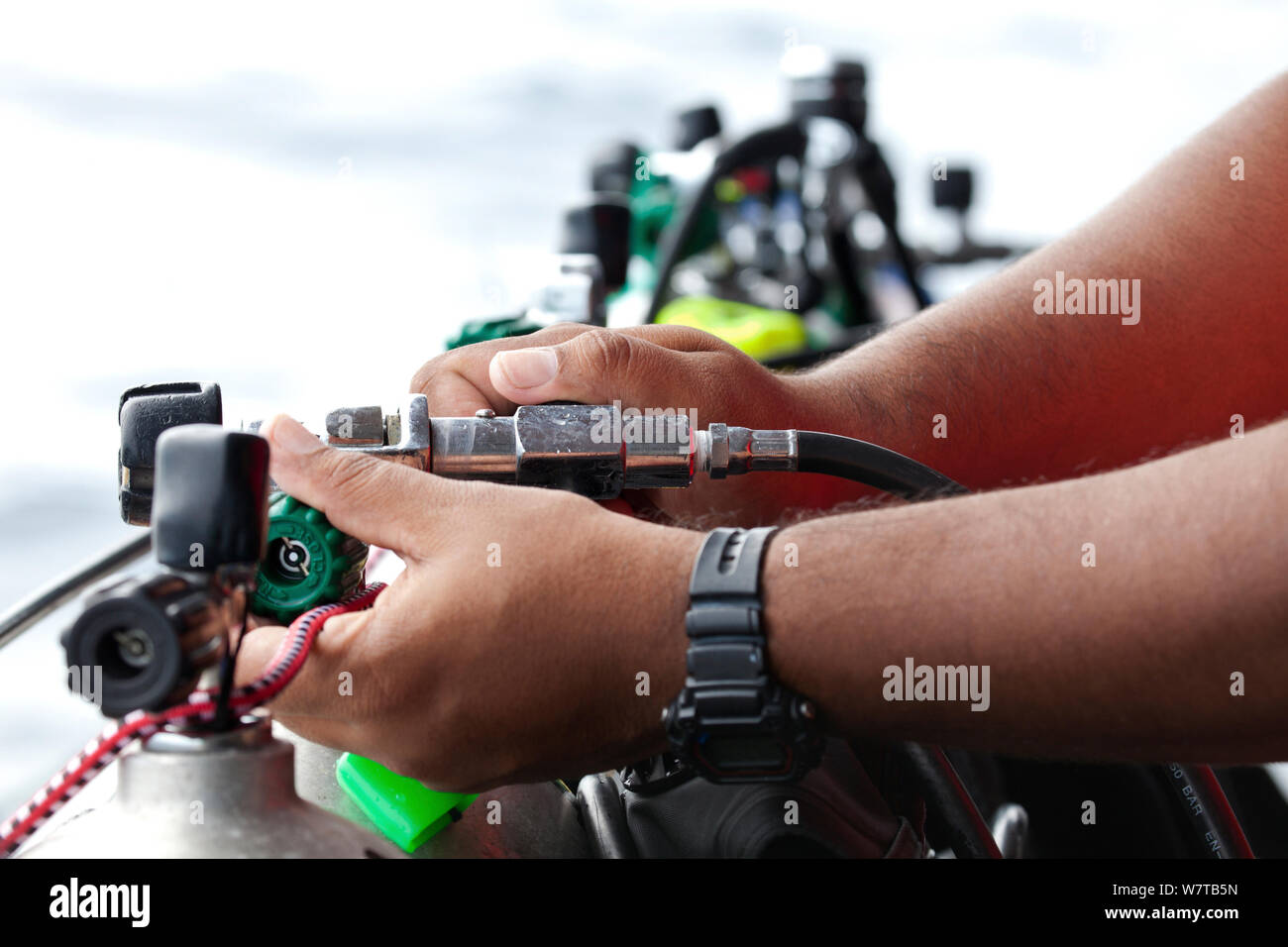 Membro di equipaggio il riempimento di scuba diving serbatoi. Isole Galapagos, Gennaio 2012. Modello rilasciato. Foto Stock